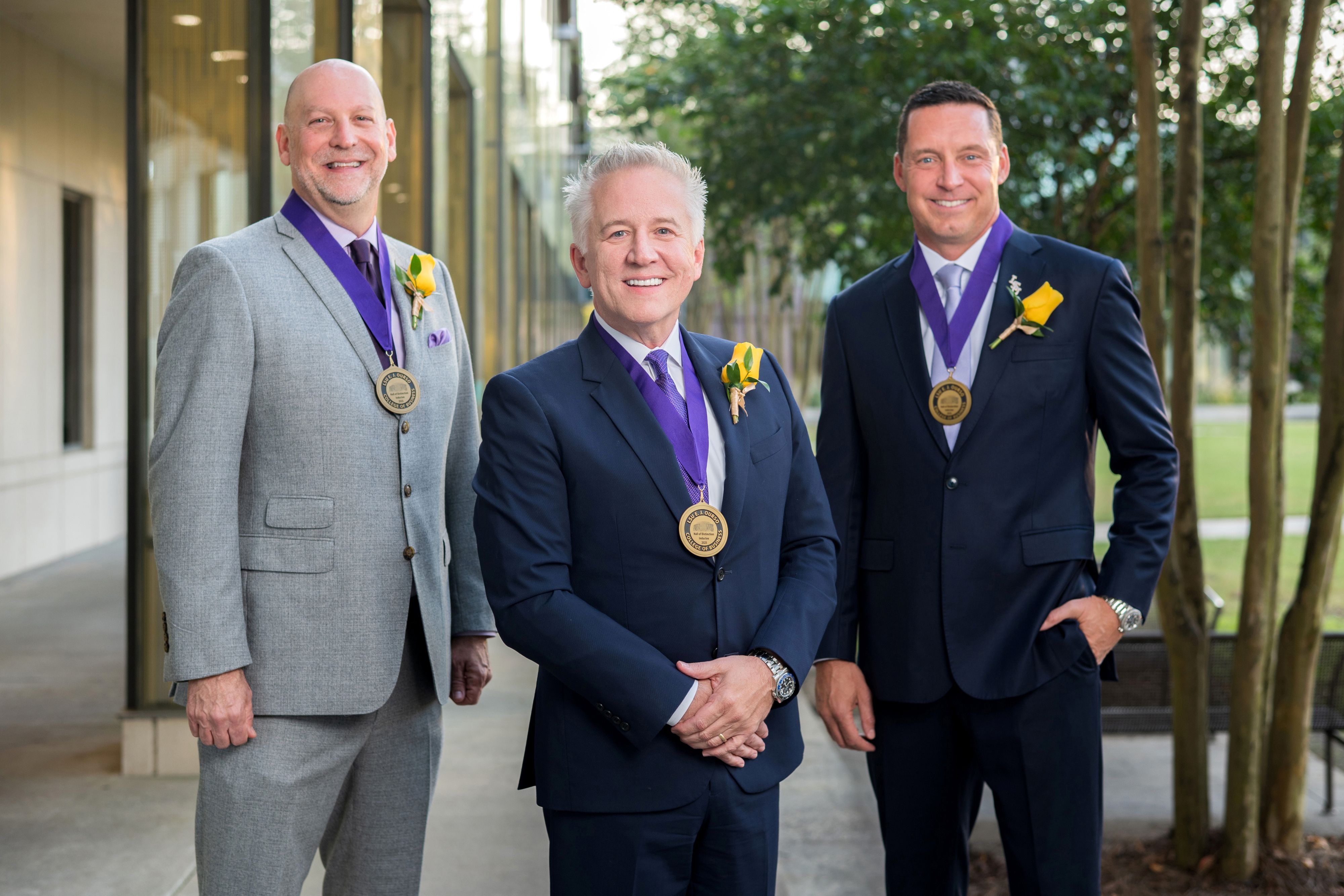 Patrick Evans, Stevie Toups, and Kurt Ainsworth stand in the BEC courtyard wearing their HOD honoree medals. 